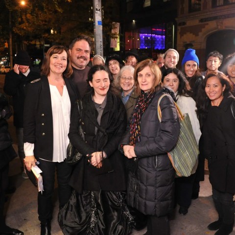 A group of people posing together on a city street at night, wearing winter clothing.