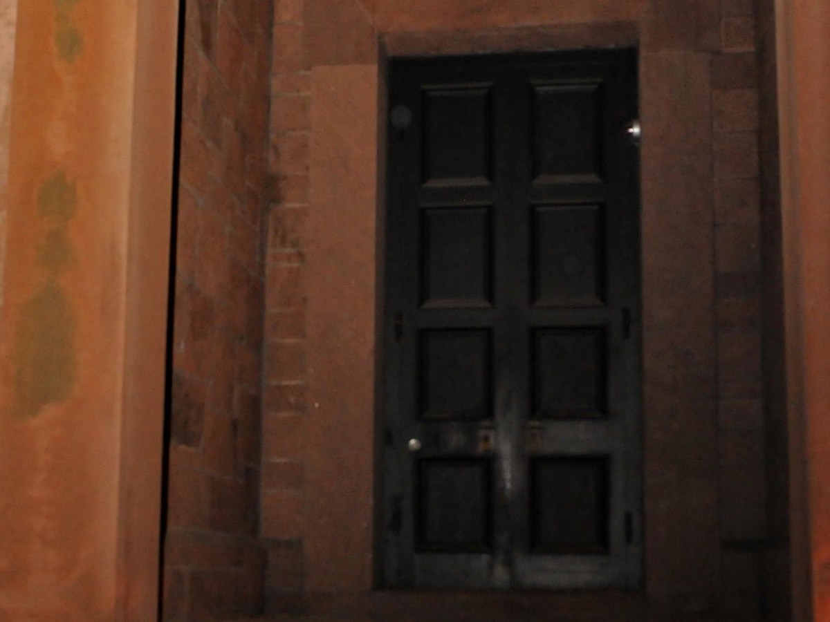 Dark wooden door set in a stone wall with slight shadows.