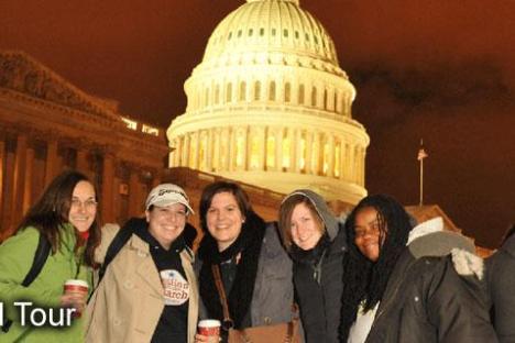 Five people smiling in front of the U.S. Capitol at night.