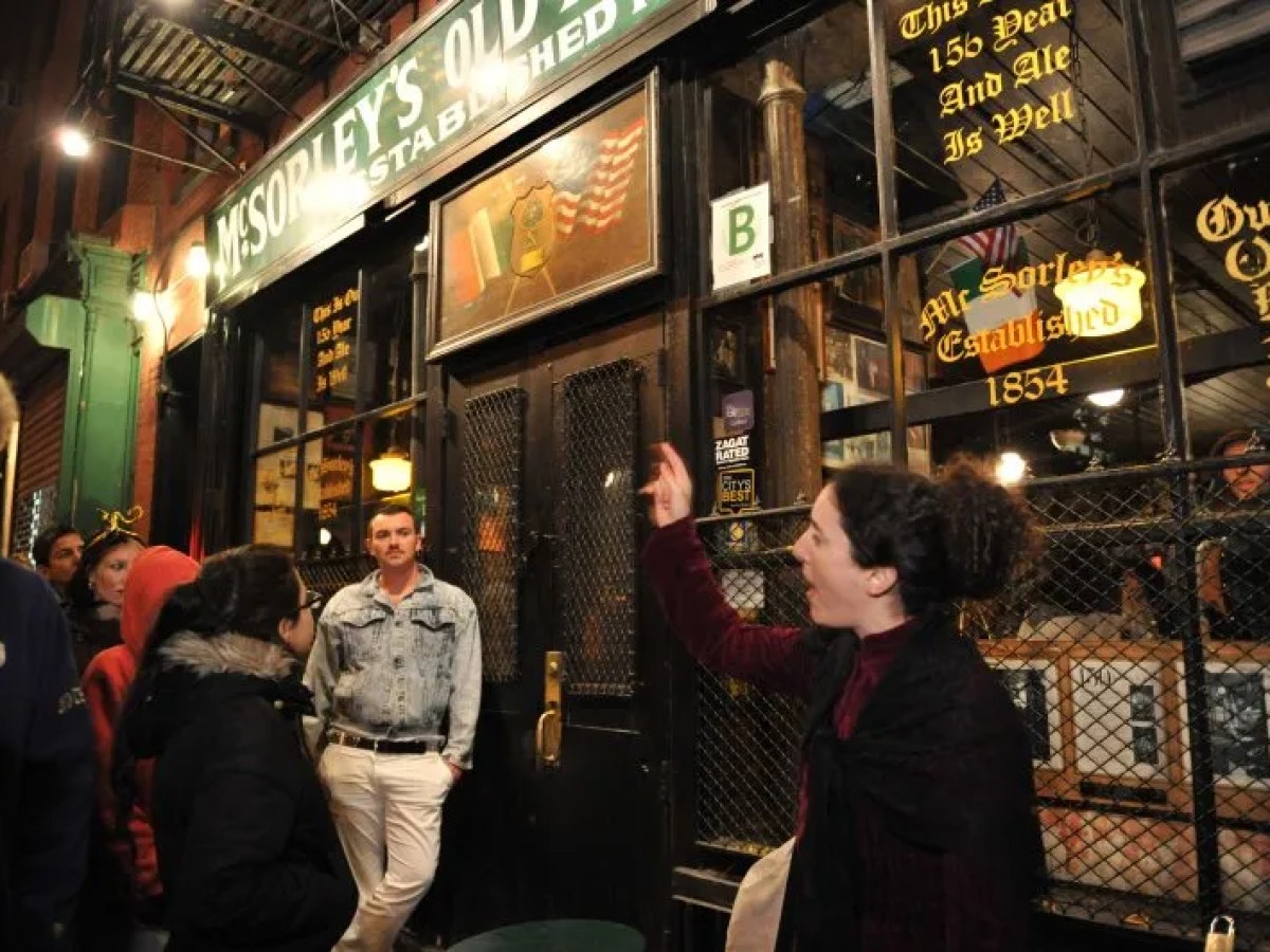 Group of people outside McSorley's Old Ale House at night.